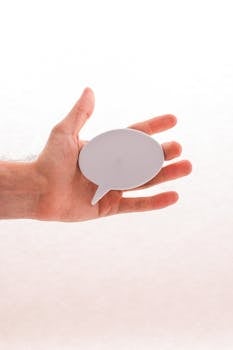 Closeup of a hand holding a blank speech bubble sign, ideal for creative concepts and mockups.